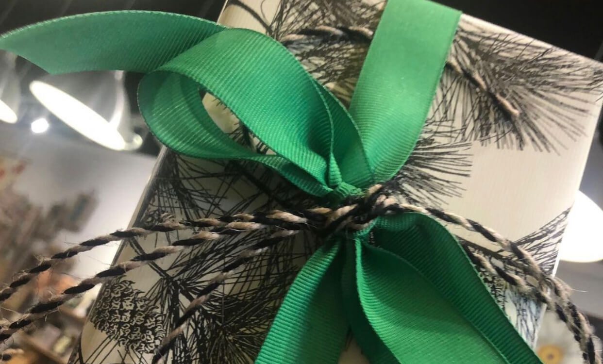 Green ribbons tied in bows on a black and white feather-patterned fabric.