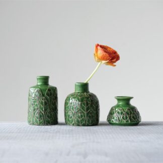 Three textured green vases, one holding an orange flower.