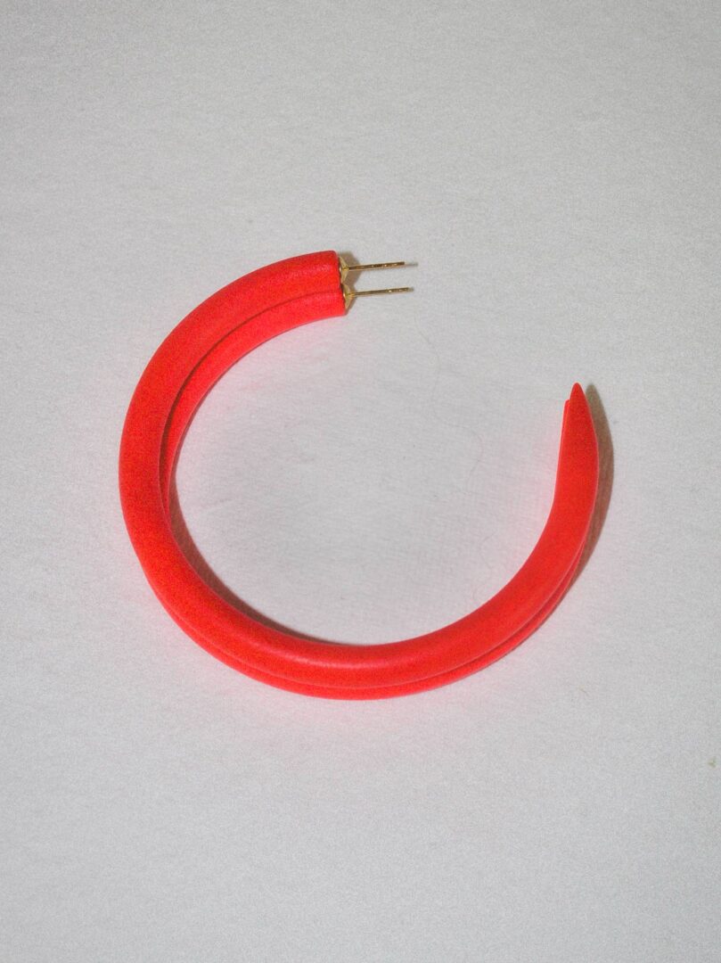 A red hoop earring with a broken clasp.