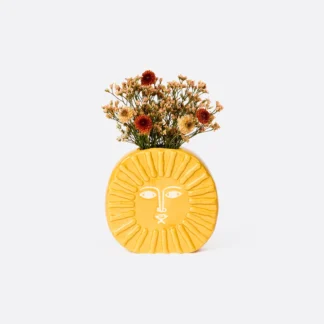 Yellow lion-shaped vase with dried flowers on white background.
