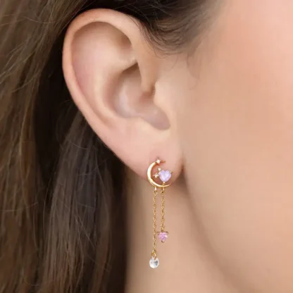 Delicate crescent moon and star drop earring on ear.