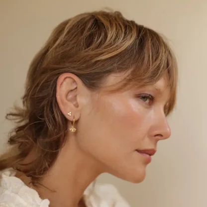 Profile of a woman with short, layered hair and gold hoop earrings.