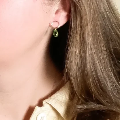 Close-up of a woman wearing a delicate green gemstone earring.