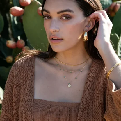 A confident woman with a natural look posing outdoors near cactus plants.