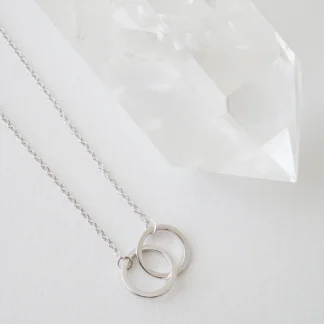 Silver interlocking circle necklace beside crystal